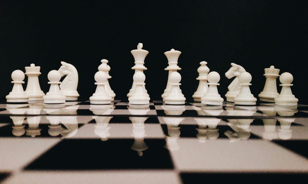 Une photo frontale de l'ensemble des pièces de couleur blanche du jeu des échecs.